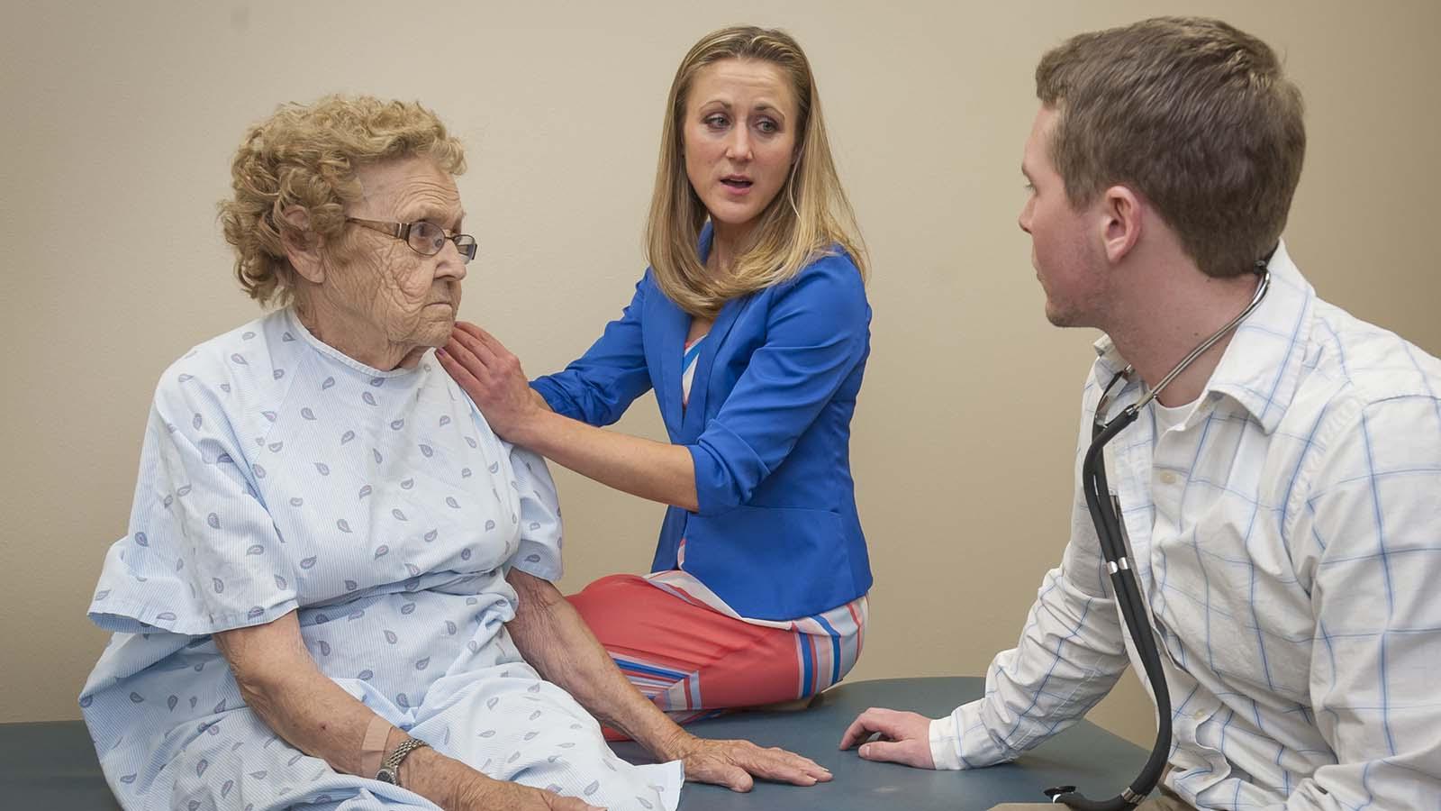 Physical therapy doctoral student and instructor meet with elderly client at the physical therapy clinic